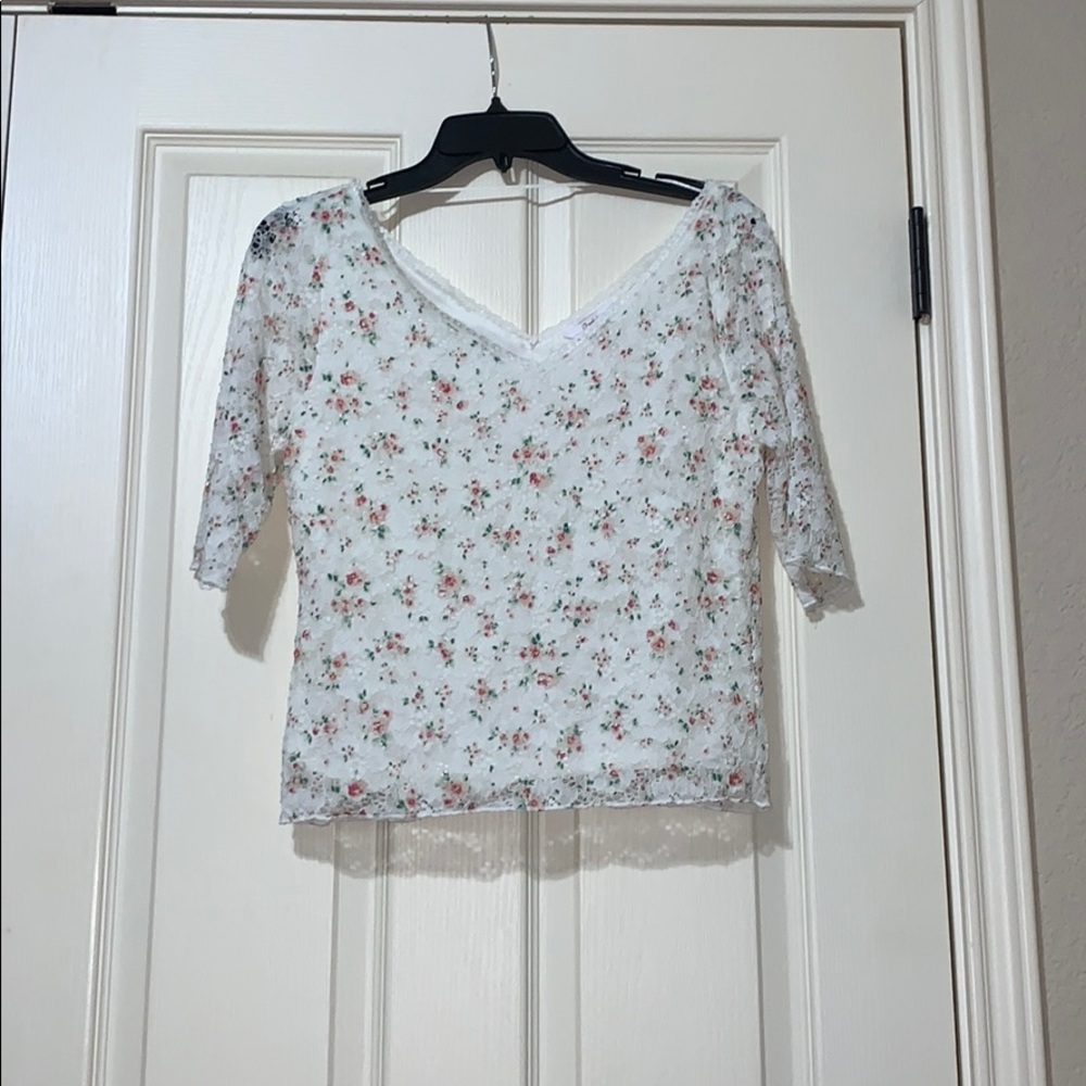 White shirt with pink flowers and green leaves.